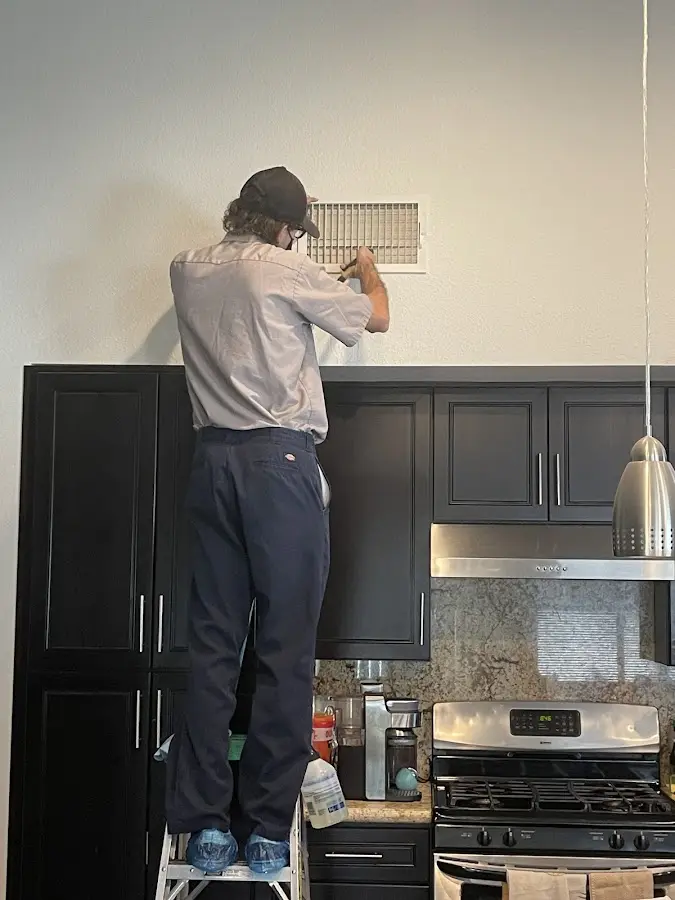 Technician inspecting an air vent during HVAC service in Prescott Valley
